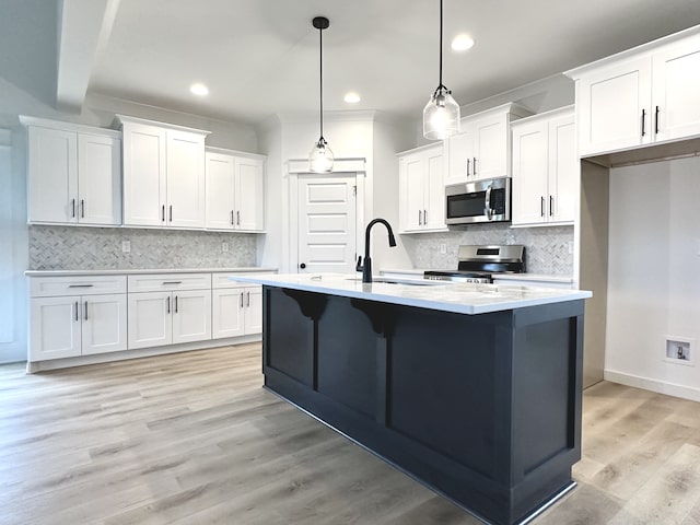 kitchen featuring white cabinets, appliances with stainless steel finishes, pendant lighting, and sink