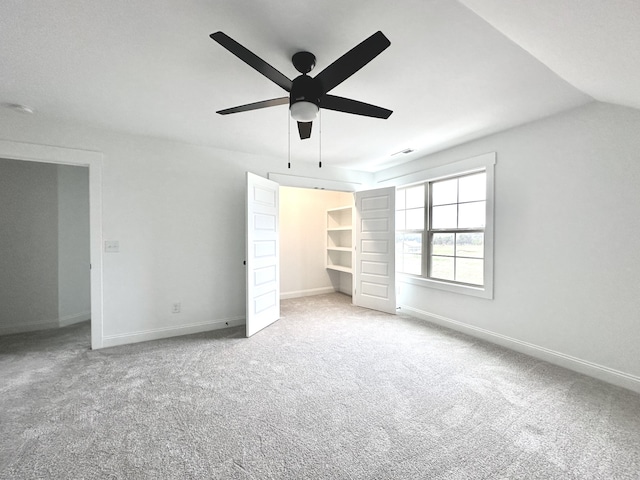 unfurnished bedroom with ceiling fan, a spacious closet, light colored carpet, lofted ceiling, and a closet