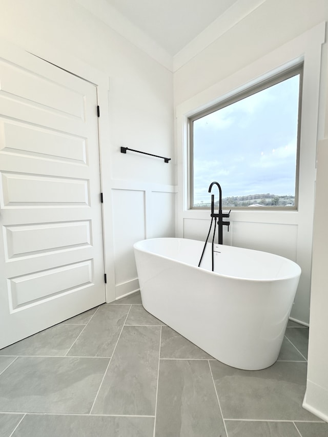 bathroom featuring a bathtub, tile patterned flooring, and ornamental molding