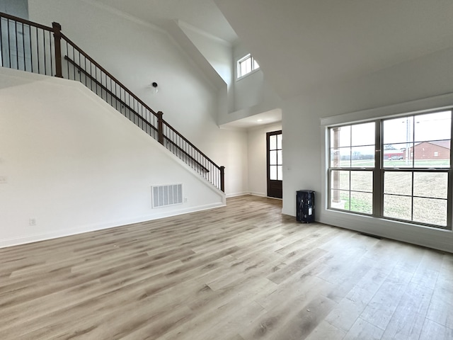 unfurnished living room featuring light wood-type flooring and a high ceiling