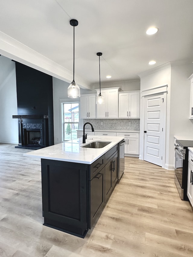 kitchen with white cabinets, sink, light hardwood / wood-style flooring, an island with sink, and stainless steel appliances