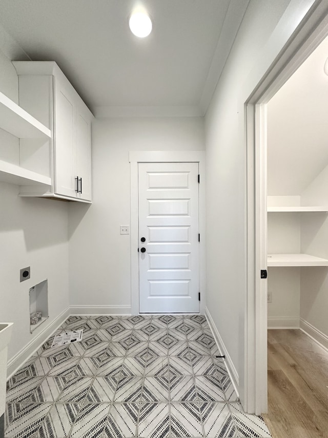 laundry area featuring electric dryer hookup, light hardwood / wood-style floors, and cabinets