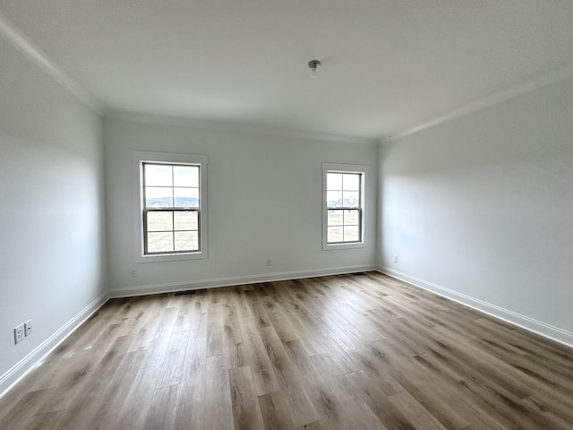 spare room with light hardwood / wood-style floors and crown molding