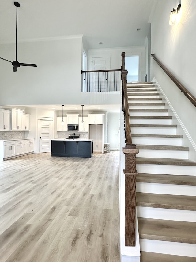 stairway with hardwood / wood-style flooring, plenty of natural light, ceiling fan, and a high ceiling