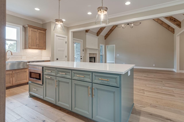 kitchen with sink, hanging light fixtures, lofted ceiling with beams, a kitchen island, and light wood-type flooring