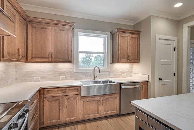 kitchen with sink, crown molding, light wood-type flooring, appliances with stainless steel finishes, and backsplash