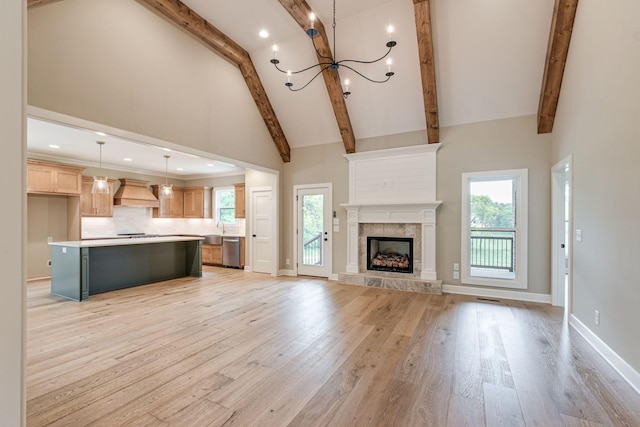 unfurnished living room featuring a fireplace, high vaulted ceiling, beamed ceiling, a notable chandelier, and light hardwood / wood-style flooring