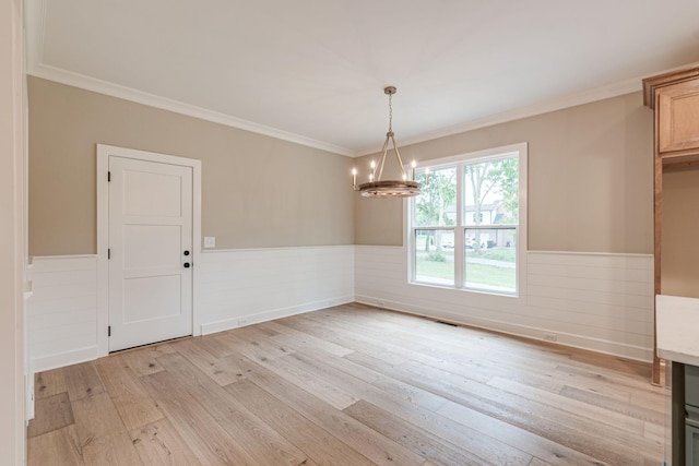 unfurnished dining area with ornamental molding, a chandelier, and light hardwood / wood-style flooring