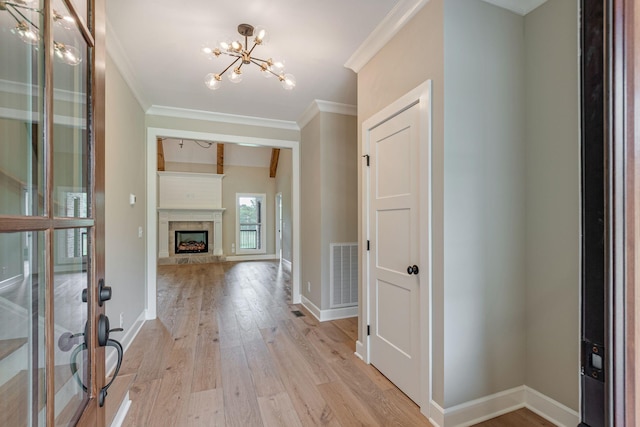 entryway with crown molding, an inviting chandelier, and light hardwood / wood-style flooring