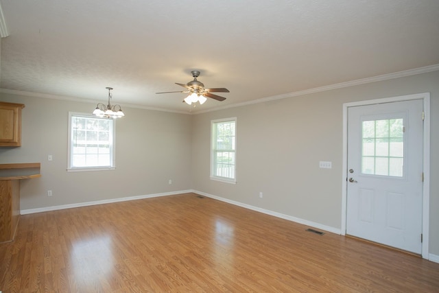 unfurnished living room with a wealth of natural light, crown molding, and ceiling fan with notable chandelier