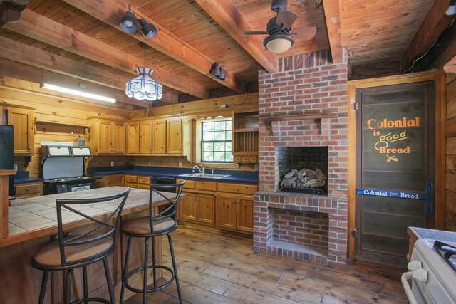 kitchen featuring tile countertops, dark wood-type flooring, sink, ceiling fan, and beamed ceiling