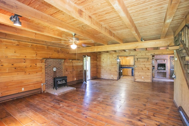 unfurnished living room with wooden ceiling, beamed ceiling, hardwood / wood-style floors, a wood stove, and wood walls