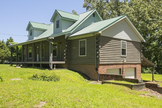 view of side of home with covered porch, a garage, and a lawn