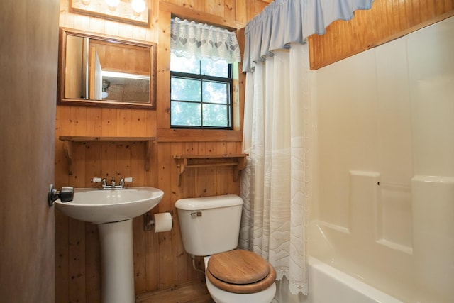 bathroom featuring wooden walls, shower / bath combo with shower curtain, and toilet