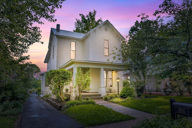 view of front of house featuring covered porch and a yard