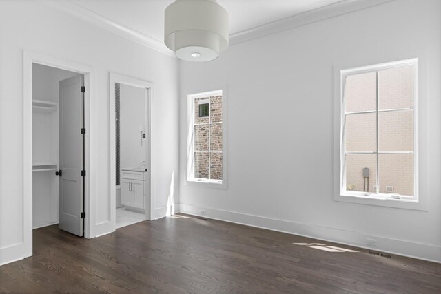 unfurnished bedroom with dark hardwood / wood-style flooring, ensuite bath, a closet, and multiple windows