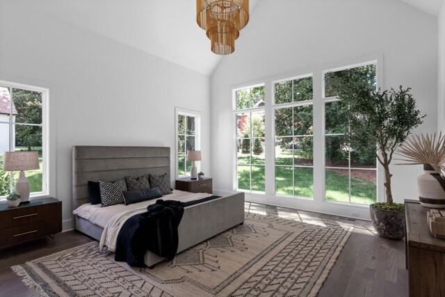 bedroom featuring high vaulted ceiling, an inviting chandelier, and hardwood / wood-style flooring