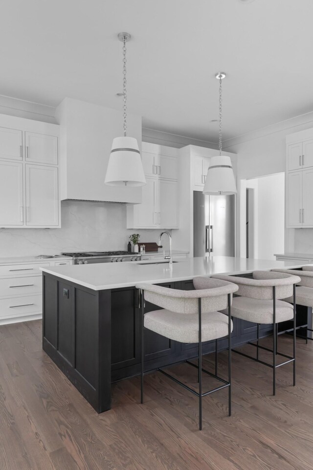 kitchen with decorative light fixtures, white cabinetry, dark hardwood / wood-style floors, and a center island with sink