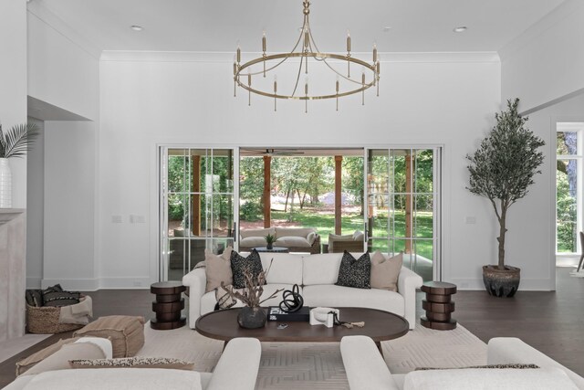 living room featuring a towering ceiling, a chandelier, hardwood / wood-style flooring, and crown molding