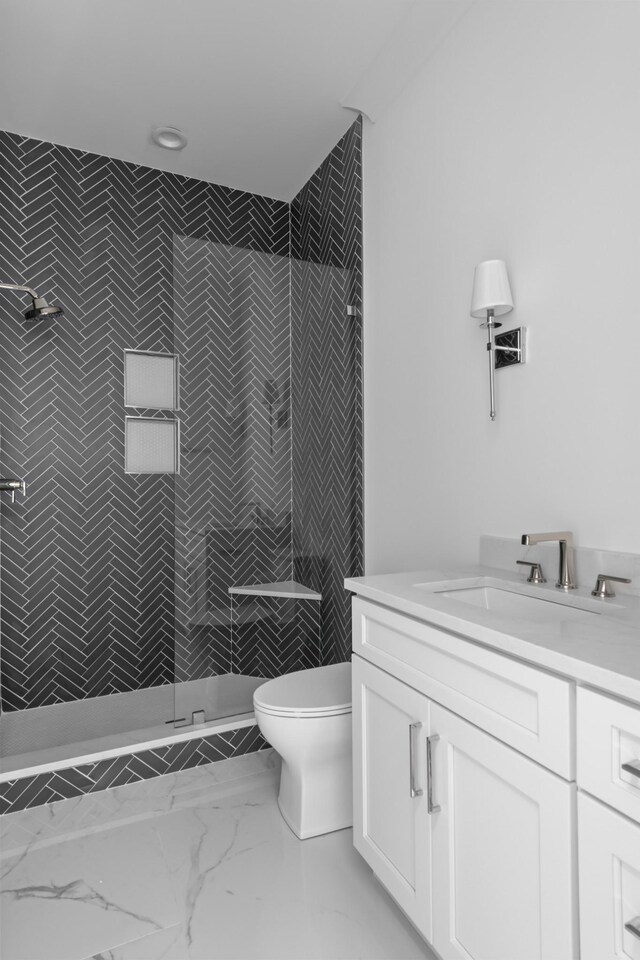 bathroom featuring a tile shower, tile flooring, toilet, and vanity