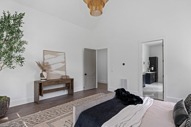 bedroom with dark hardwood / wood-style floors, high vaulted ceiling, and connected bathroom