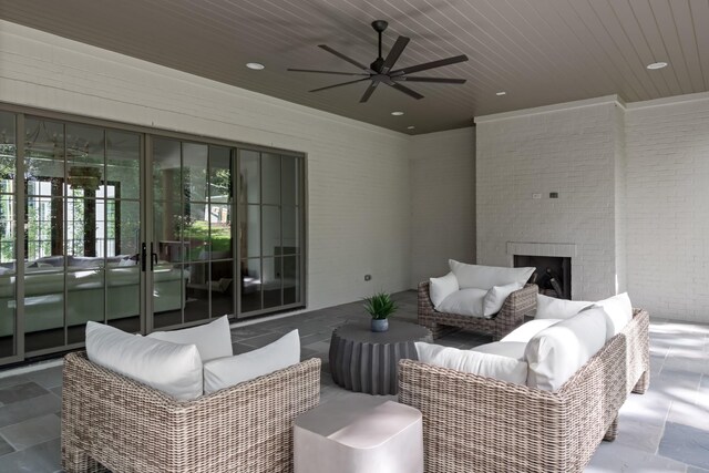 exterior space featuring ceiling fan, an outdoor brick fireplace, brick wall, dark tile flooring, and wooden ceiling