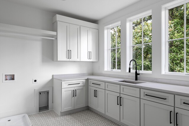 laundry area with a healthy amount of sunlight, sink, electric dryer hookup, and light tile floors