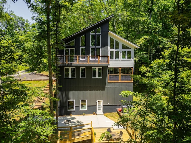 rear view of house with a sunroom, a balcony, and a patio