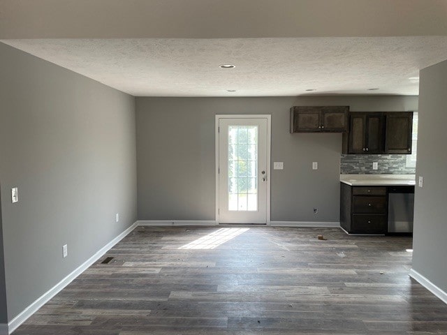 kitchen with dark brown cabinetry, decorative backsplash, dark wood-type flooring, and a textured ceiling