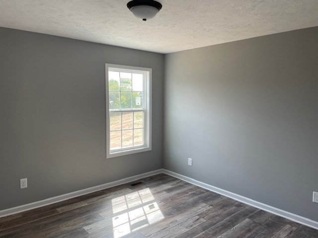 spare room featuring dark wood-type flooring and a textured ceiling