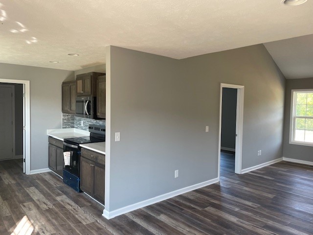 kitchen featuring lofted ceiling, black electric range oven, dark wood-type flooring, and backsplash