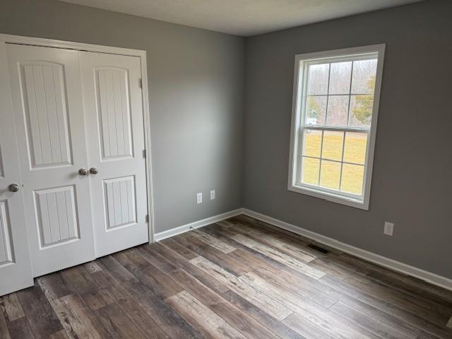 unfurnished bedroom with dark hardwood / wood-style flooring and a closet