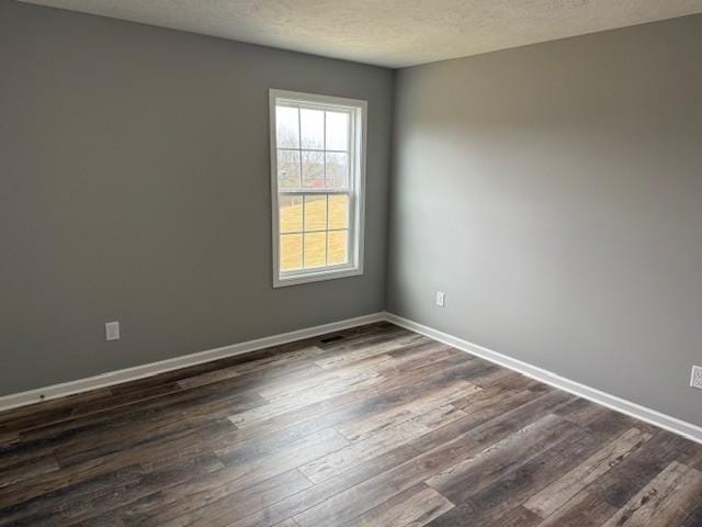 empty room with dark wood-type flooring and a textured ceiling