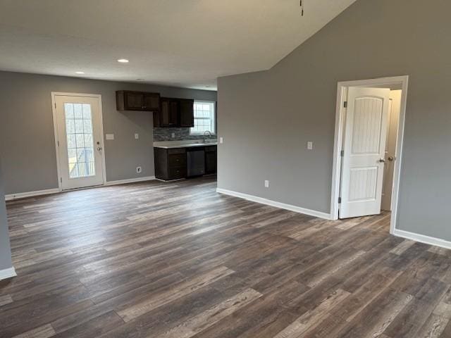 unfurnished living room with sink, dark hardwood / wood-style floors, and vaulted ceiling