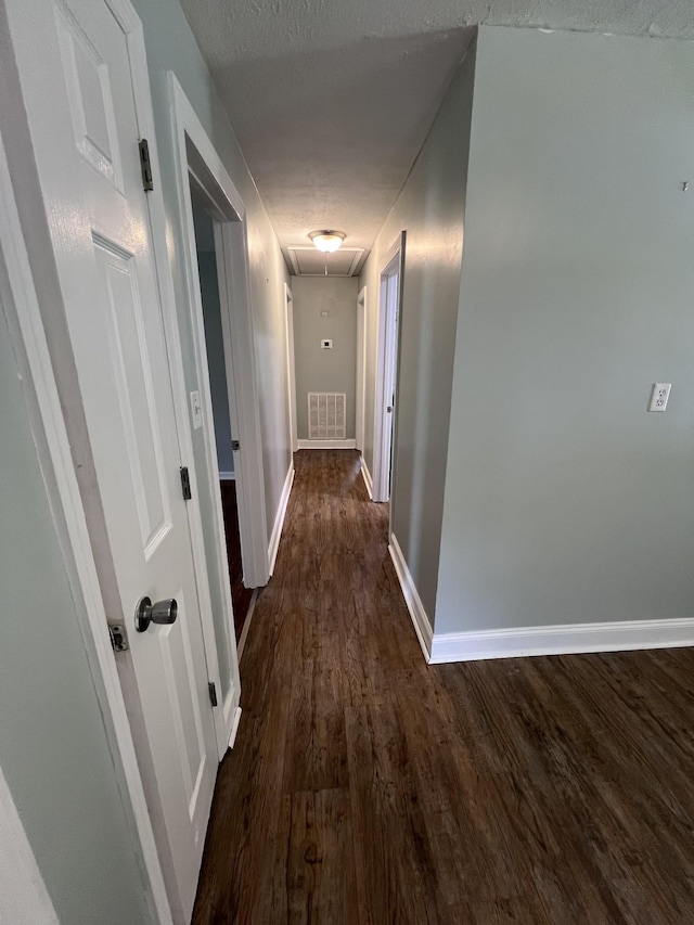 hall with a textured ceiling and dark hardwood / wood-style floors