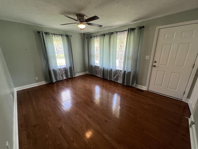 interior space with a textured ceiling, ceiling fan, and dark wood-type flooring