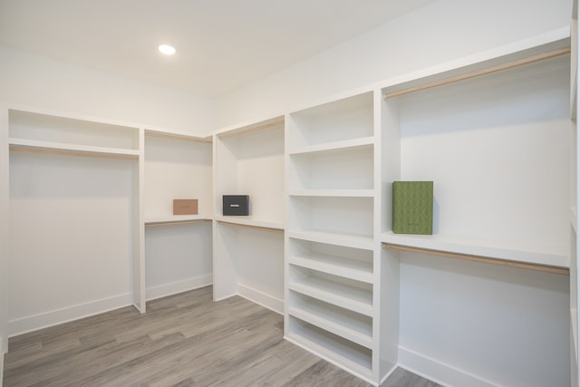 spacious closet with built in desk and hardwood / wood-style flooring