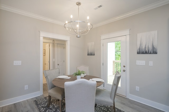 dining space featuring ornamental molding, an inviting chandelier, and hardwood / wood-style flooring