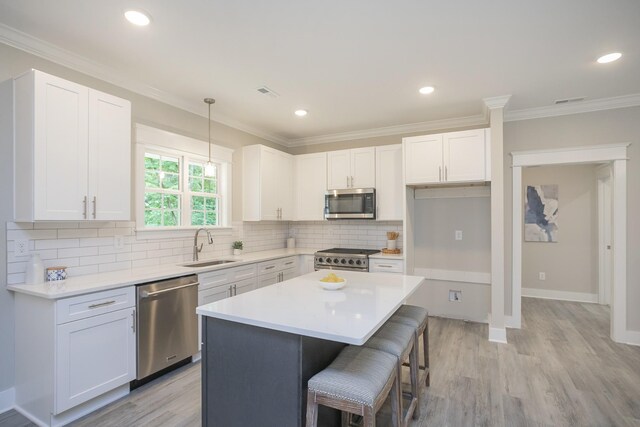 kitchen featuring a center island, light hardwood / wood-style floors, stainless steel appliances, white cabinets, and tasteful backsplash