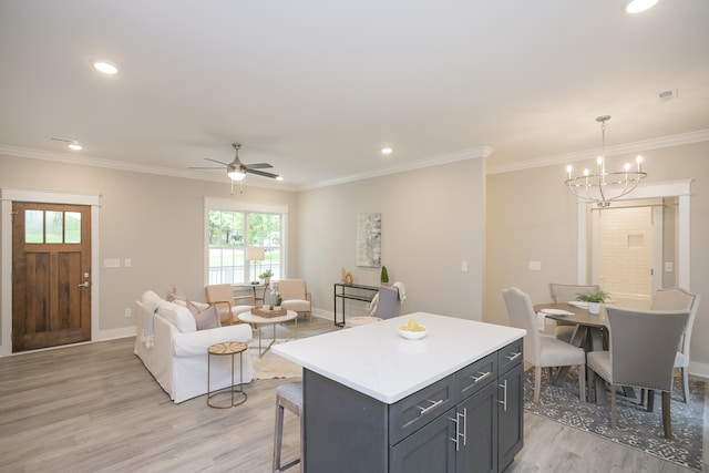 kitchen with decorative light fixtures, light wood-type flooring, ceiling fan with notable chandelier, a center island, and ornamental molding