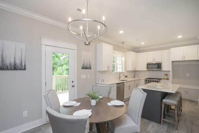 dining area featuring light hardwood / wood-style floors, sink, crown molding, and a notable chandelier