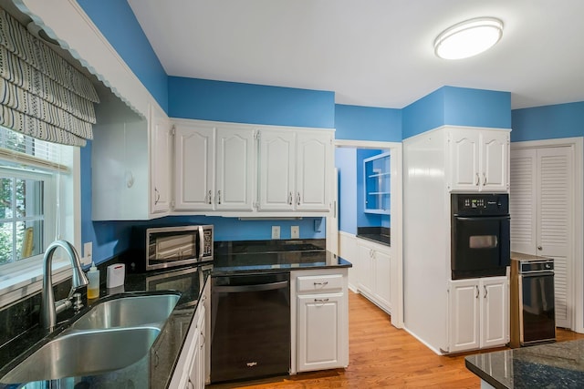 kitchen with white cabinetry, sink, black appliances, and light hardwood / wood-style flooring