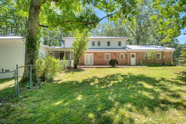 back of property with a lawn, a sunroom, and a patio