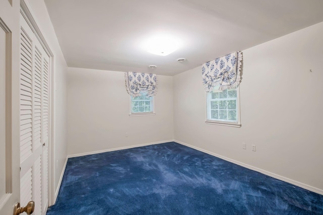 empty room featuring dark colored carpet and a chandelier