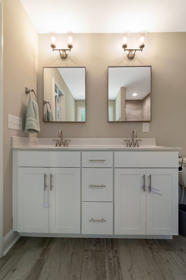 bathroom featuring wood-type flooring, double sink, and vanity with extensive cabinet space