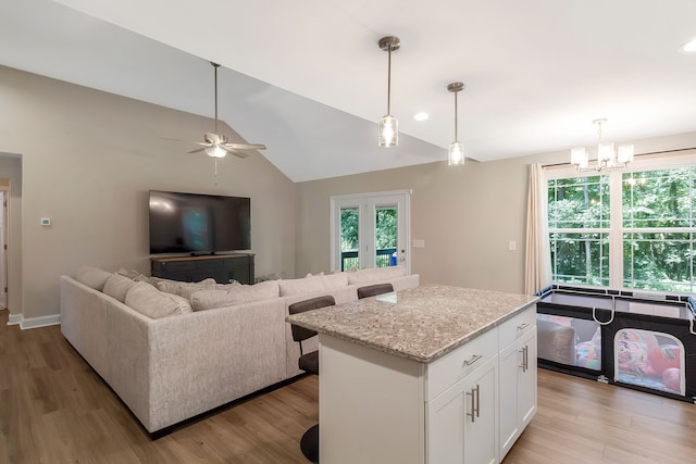 kitchen with hanging light fixtures, white cabinets, a center island, and light wood-type flooring