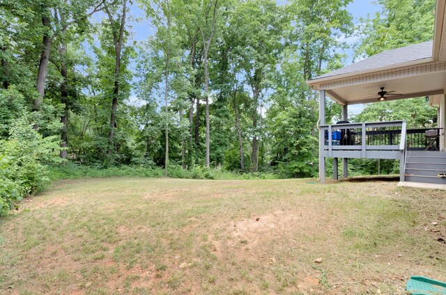 view of yard with a deck and ceiling fan