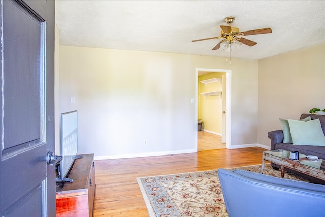 living room with ceiling fan, a textured ceiling, and hardwood / wood-style flooring