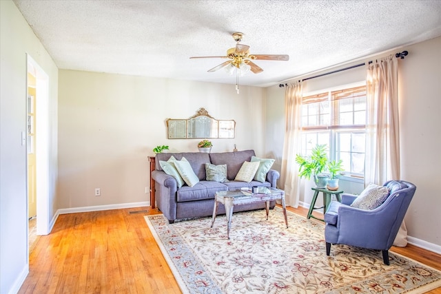 living room featuring ceiling fan, a textured ceiling, and light wood-type flooring