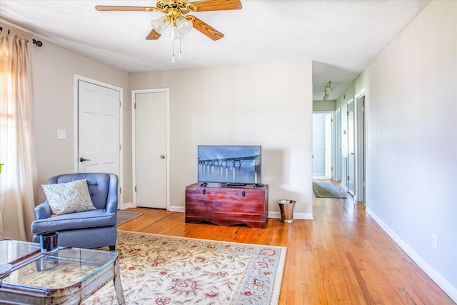 living room with hardwood / wood-style floors, ceiling fan, and a textured ceiling